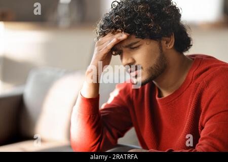 Portrait d'un jeune Indien déprimé assis sur un canapé à la maison Banque D'Images