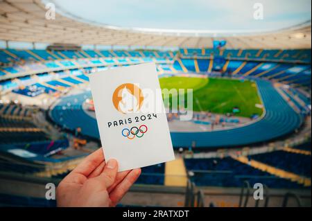 PARIS, FRANCE, 7 JUILLET 2023 : icône des Jeux olympiques d'été Paris 2024 organisée par l'athlète. Stade olympique moderne en arrière-plan. Fond d'écran pour Summer Olymp Banque D'Images