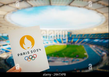 PARIS, FRANCE, le 7 JUILLET 2023 : embrasser le symbole : l'athlète détient l'emblème emblématique des Jeux olympiques d'été de Paris 2024, avec Modern Stadium comme Majestic Backdr Banque D'Images