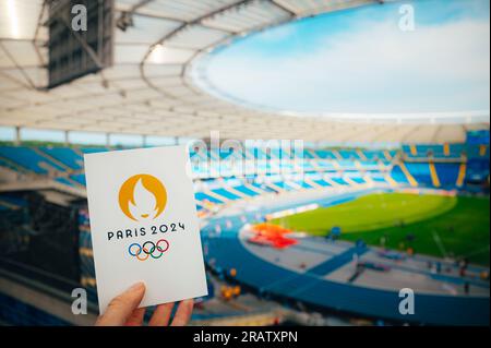 PARIS, FRANCE, le 7 JUILLET 2023 : embrasser le symbole : l'athlète détient l'emblème emblématique des Jeux olympiques d'été de Paris 2024, avec Modern Stadium comme Majestic Backdr Banque D'Images