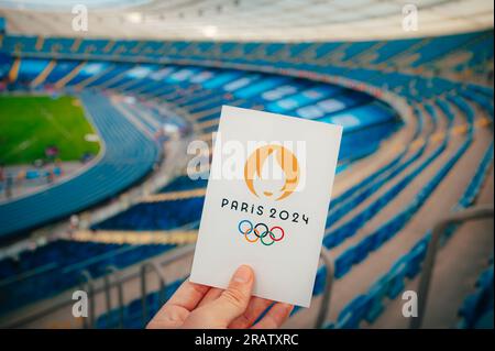 PARIS, FRANCE, le 7 JUILLET 2023 : embrasser le symbole : l'athlète détient l'emblème emblématique des Jeux olympiques d'été de Paris 2024, avec Modern Stadium comme Majestic Backdr Banque D'Images