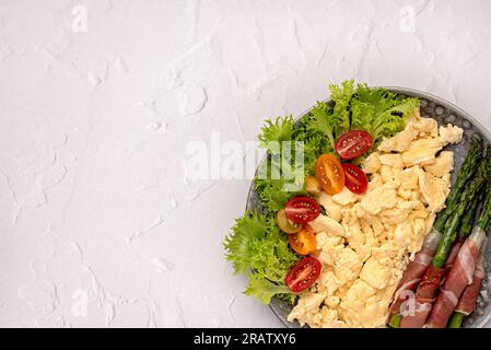 Photographie de nourriture vierge de petit déjeuner, oeuf brouillé, asperges frites, prosciutto, tomate, feuille, laitue, brunch, fond, repas, alimentation Banque D'Images