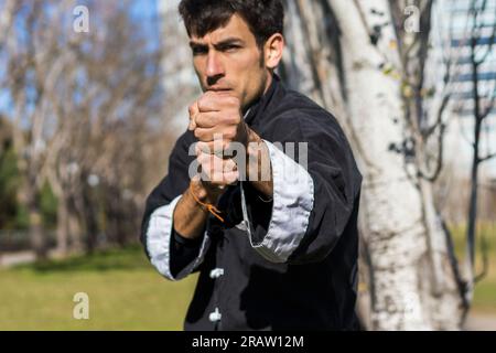 Portrait d'un jeune combattant athlétique d'arts martiaux pratiquant des coups de pied en regardant la caméra Banque D'Images