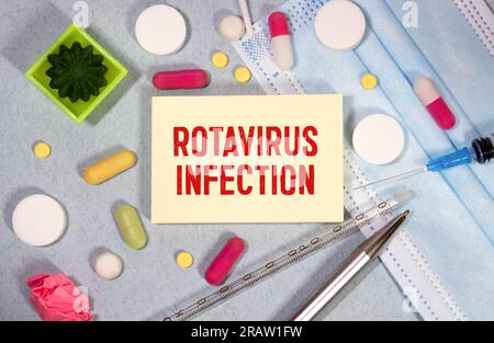 Concept médical. Sur une surface grise, une seringue, un thermomètre, un stéthoscope, une plaquette thermoformée et un bloc-notes portant l'inscription : infection à rotavirus Banque D'Images