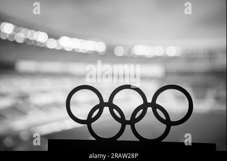 PARIS, FRANCE, 7 JUILLET 2023 : photo en noir et blanc. Silhouette d'anneaux olympiques embrassant un stade olympique moderne en arrière-plan. Paris Summer Oly Banque D'Images