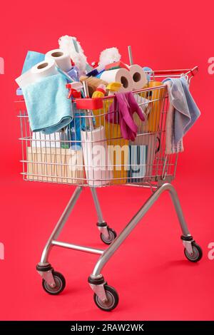 Panier rempli de fournitures de nettoyage sur fond rouge Banque D'Images