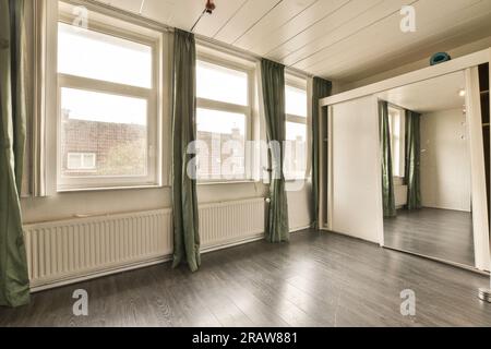 une pièce vide avec des planchers de bois et des rideaux verts sur la fenêtre est ouverte pour laisser entrer la lumière dans la pièce Banque D'Images