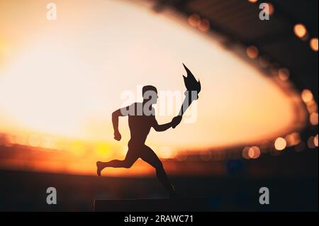 Silhouette de l'athlète masculin portant le relais de la flamme, illuminant le stade moderne d'athlétisme. Un instantané captivant pour le Summer Game 2024 Banque D'Images