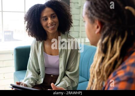 Heureux divers collègues d'affaires masculins et féminins occasionnels assis sur le canapé parlant au bureau. Affaires, travail d'équipe et travail, inchangés. Banque D'Images