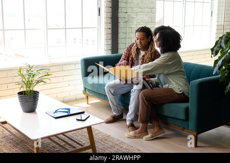 Divers collègues d'affaires occasionnels masculins et féminins assis sur le canapé discutant des documents au bureau. Affaires, travail d'équipe et travail, inchangés. Banque D'Images