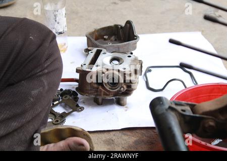 Mécanicien répare un motercycle. Un homme travaille comme mécanicien dans un atelier de réparation de motos local. Odisha, Inde. Banque D'Images