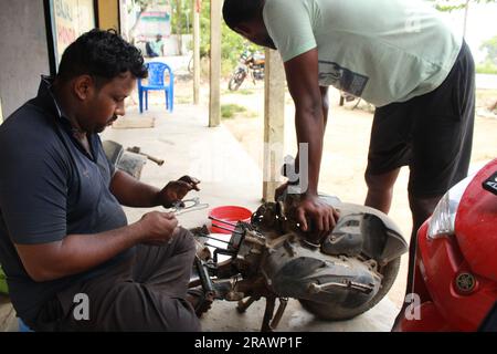 Mécanicien répare un motercycle. Un homme travaille comme mécanicien dans un atelier de réparation de motos local. Odisha, Inde. Banque D'Images