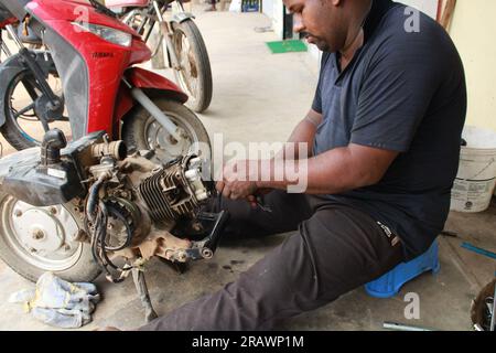 Mécanicien répare un motercycle. Un homme travaille comme mécanicien dans un atelier de réparation de motos local. Odisha, Inde. Banque D'Images