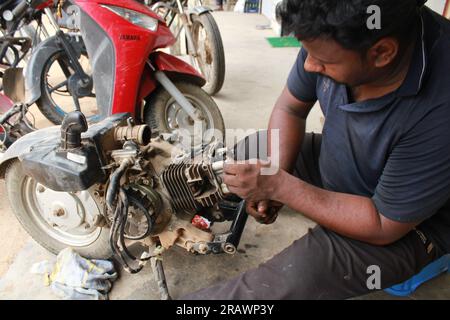 Mécanicien répare un motercycle. Un homme travaille comme mécanicien dans un atelier de réparation de motos local. Odisha, Inde. Banque D'Images