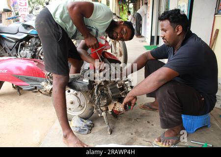 Mécanicien répare un motercycle. Un homme travaille comme mécanicien dans un atelier de réparation de motos local. Odisha, Inde. Banque D'Images