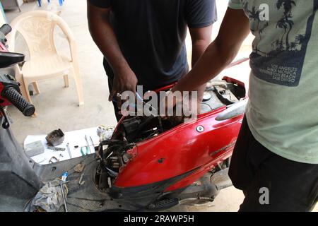 Mécanicien répare un motercycle. Un homme travaille comme mécanicien dans un atelier de réparation de motos local. Odisha, Inde. Banque D'Images