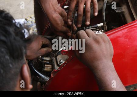 Mécanicien répare un motercycle. Un homme travaille comme mécanicien dans un atelier de réparation de motos local. Odisha, Inde. Banque D'Images