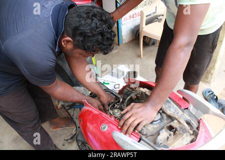 Mécanicien répare un motercycle. Un homme travaille comme mécanicien dans un atelier de réparation de motos local. Odisha, Inde. Banque D'Images