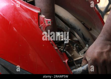 Mécanicien répare un motercycle. Un homme travaille comme mécanicien dans un atelier de réparation de motos local. Odisha, Inde. Banque D'Images