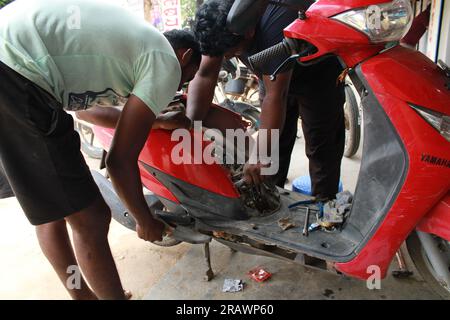 Mécanicien répare un motercycle. Un homme travaille comme mécanicien dans un atelier de réparation de motos local. Odisha, Inde. Banque D'Images