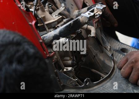 Mécanicien répare un motercycle. Un homme travaille comme mécanicien dans un atelier de réparation de motos local. Odisha, Inde. Banque D'Images