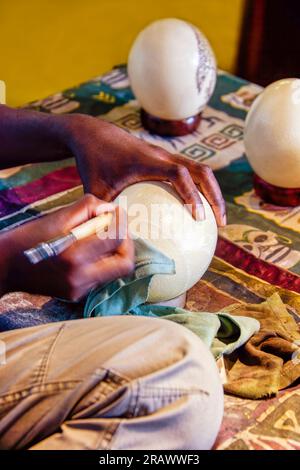 artisan africain sculptant traditionnellement à la main une coquille d'autruche Banque D'Images