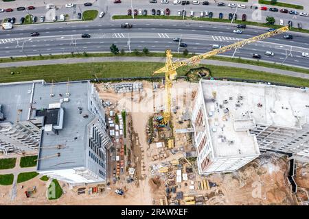 grue jaune travaillant sur bâtiment résidentiel à plusieurs étages en construction. vue aérienne de dessus du drone volant. Banque D'Images