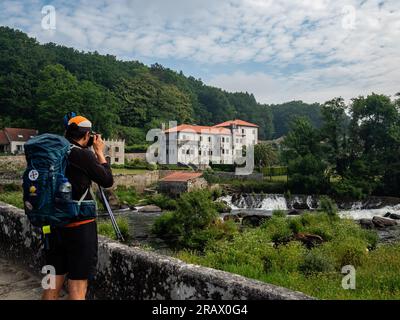 3 juin 2023, A Ponte Maceira, Espagne : un pèlerin est vu prenant une photo d'un pont d'une belle paroisse. Le Camino de Santiago (le chemin de St. James) est un vaste réseau d'anciennes routes de pèlerins qui s'étendent à travers l'Europe et se rejoignent sur la tombe de Saint James (Santiago en espagnol) à Santiago de Compostelle, Espagne. Finisterre était à la fois la fin du monde connu jusqu'à ce que Colomb change les choses et la destination finale de nombreux pèlerins qui ont fait le voyage à Santiago au cours des siècles passés. Les pèlerins des siècles passés ont également continué vers le nord jusqu'au Santuario de Nuestra se Banque D'Images