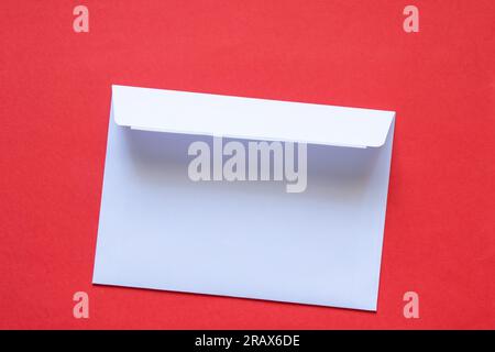 l'enveloppe de courrier blanche en papier repose sur un fond rouge gros plan Banque D'Images