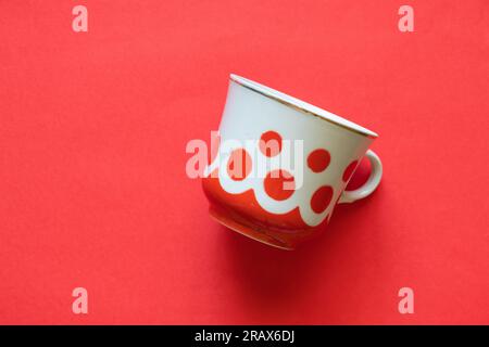 vieille tasse avec pois rouges sur fond rouge gros plan Banque D'Images