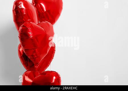 Beaucoup de ballons en forme de coeur rouge sur fond blanc, gros plan. Espace pour le texte Banque D'Images