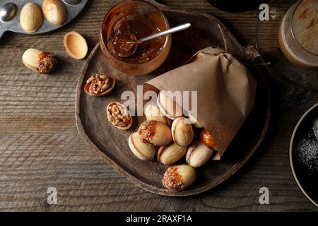 Biscuits faits maison en forme de noix fraîchement cuits, lait concentré bouilli et tasse de café sur la table en bois, plat Banque D'Images