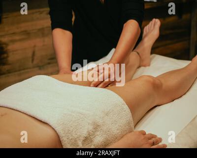 Masseur faisant un massage anti-cellulite des cuisses des jambes dans le spa de bien-être de salon close-up. masseur faisant un massage des jambes à la femme. Banque D'Images