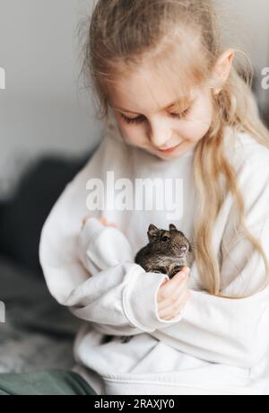 Jeune fille jouant avec mignon écureuil degu chilien. Animal mignon assis sur la main d'un enfant Banque D'Images