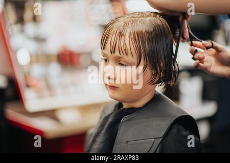 Jeune garçon se faisant couper les cheveux dans un salon de coiffure Banque D'Images