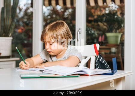 Mignon petit garçon faisant des devoirs pour l'école, écrivant dans le cahier d'excersice Banque D'Images