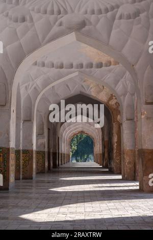 Vue en perspective d'une rangée d'arches alignées autour de la tombe de l'empereur moghol Jahangir dans le jardin Char Bagh, Lahore, Punjab, Pakistan avec lumière latérale Banque D'Images