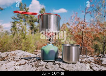 Cuisson du petit déjeuner ou de la soupe dans une casserole sur une cuisinière à gaz à la randonnée ou au camping. Matériel et ustensiles de cuisine Banque D'Images