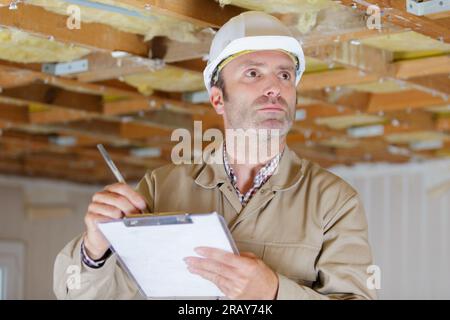 Homme builder ou d'ouvrier en casque writing on clipboard Banque D'Images
