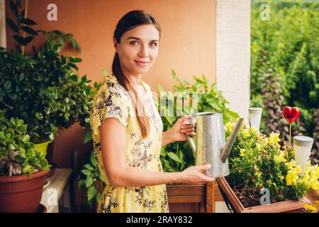 Portrait de la belle femme arroser des plantes vertes sur le balcon, petit jardin confortable dans l'appartement Banque D'Images