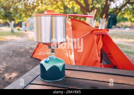 Cuisson du petit déjeuner ou de la soupe dans une casserole sur une cuisinière à gaz à la randonnée ou tente de camping. Matériel et ustensiles de cuisine Banque D'Images