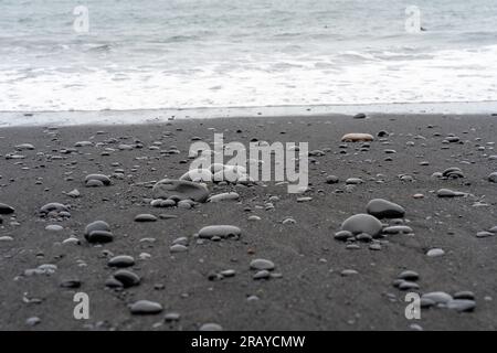 Les vagues se lavent contre Reynisfjara Black Sand Beach en Islande Banque D'Images