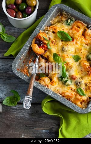 Pâtes cuites au four avec olives colorées, poivrons et tomates. Gratin de pâtes et légumes dans un plat allant au four Banque D'Images