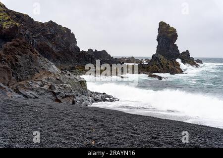 Vagues se lavant sur la plage de sable noir de Djupalonssandur en Islande Banque D'Images