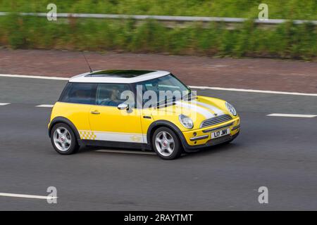 2001 jaune Mini coupe 1,6 Cooper Euro 3 3dr, Hatchback essence 1598 cc ; voyageant à grande vitesse sur l'autoroute M6 dans le Grand Manchester, Royaume-Uni Banque D'Images