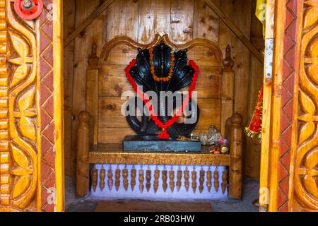 28 juin 2023, Nagthat, Uttarakhand, Inde. La divinité hindoue Nag Devta ou le Dieu serpent figure en pierre noire dans un temple avec un intérieur en bois. Banque D'Images