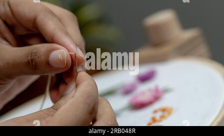 Aiguille à enfiler à la main pour femmes pour broderie à l'aiguille, mains rapprochées avec des fils. Banque D'Images