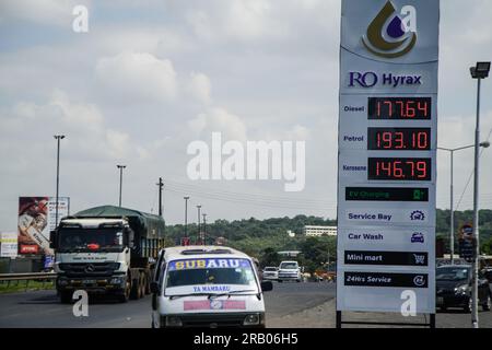 Véhicules à moteur, passez devant un panneau d'affichage à la station-service montrant la hausse récente des prix du carburant au Kenya. Le coût du carburant a grimpé de 8% à 16% après le doublement de la taxe sur la valeur ajoutée sur le carburant, à la suite de l'adoption de la loi de finances controversée de 2023. Banque D'Images