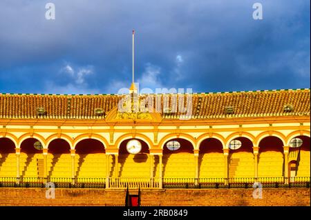 Séville, Espagne - 20 janvier 2023 : aménagement intérieur du bâtiment médiéval. Une horloge orne les gradins sous un porche avec des arcs et des colonnes Banque D'Images