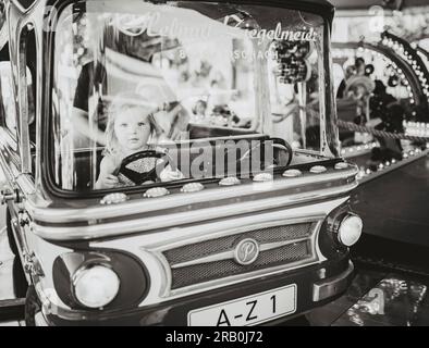 Petite fille chevauchant carrousel à un parc d'expositions Banque D'Images